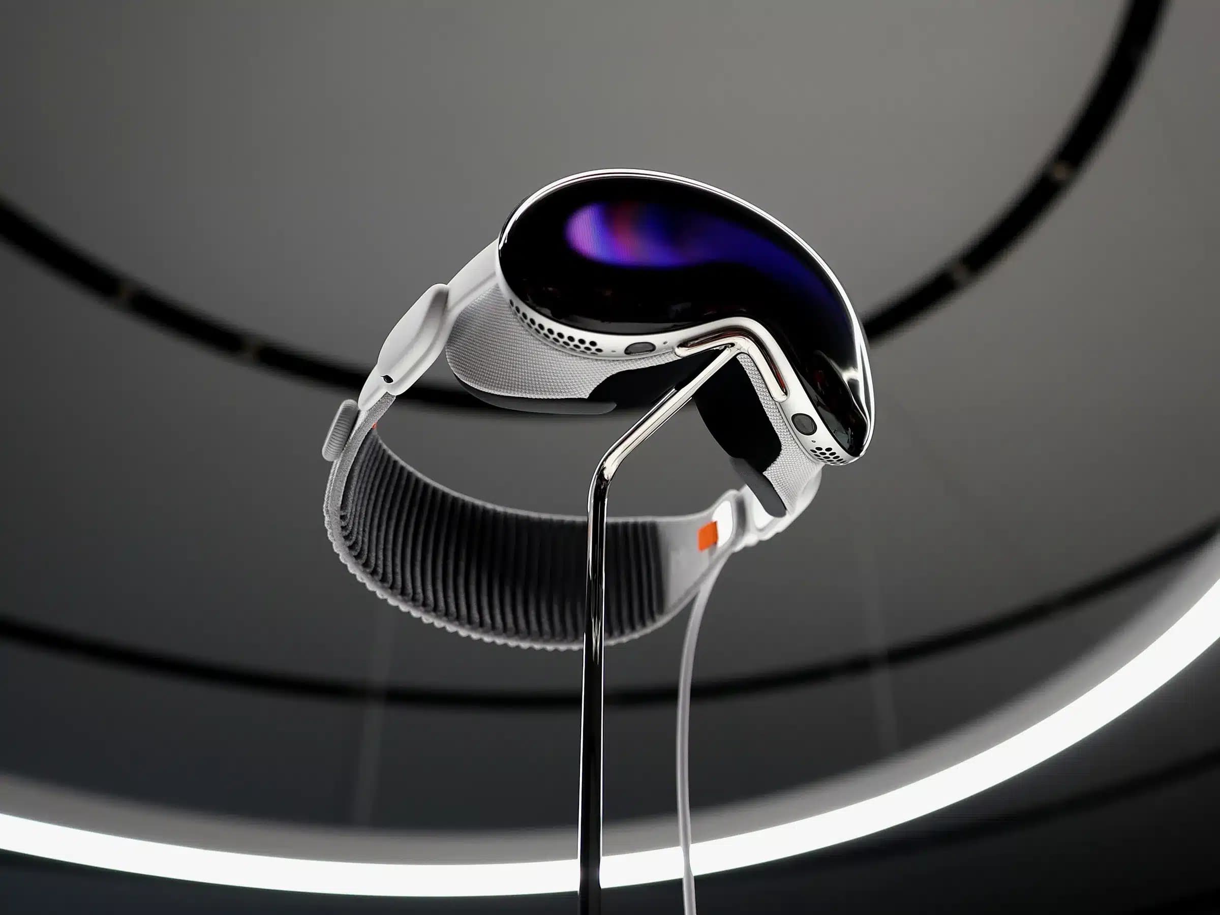 A sleek, futuristic virtual reality headset with a reflective visor, white straps, and a dark oval display, mounted on a stand with a circular ceiling light in the background.