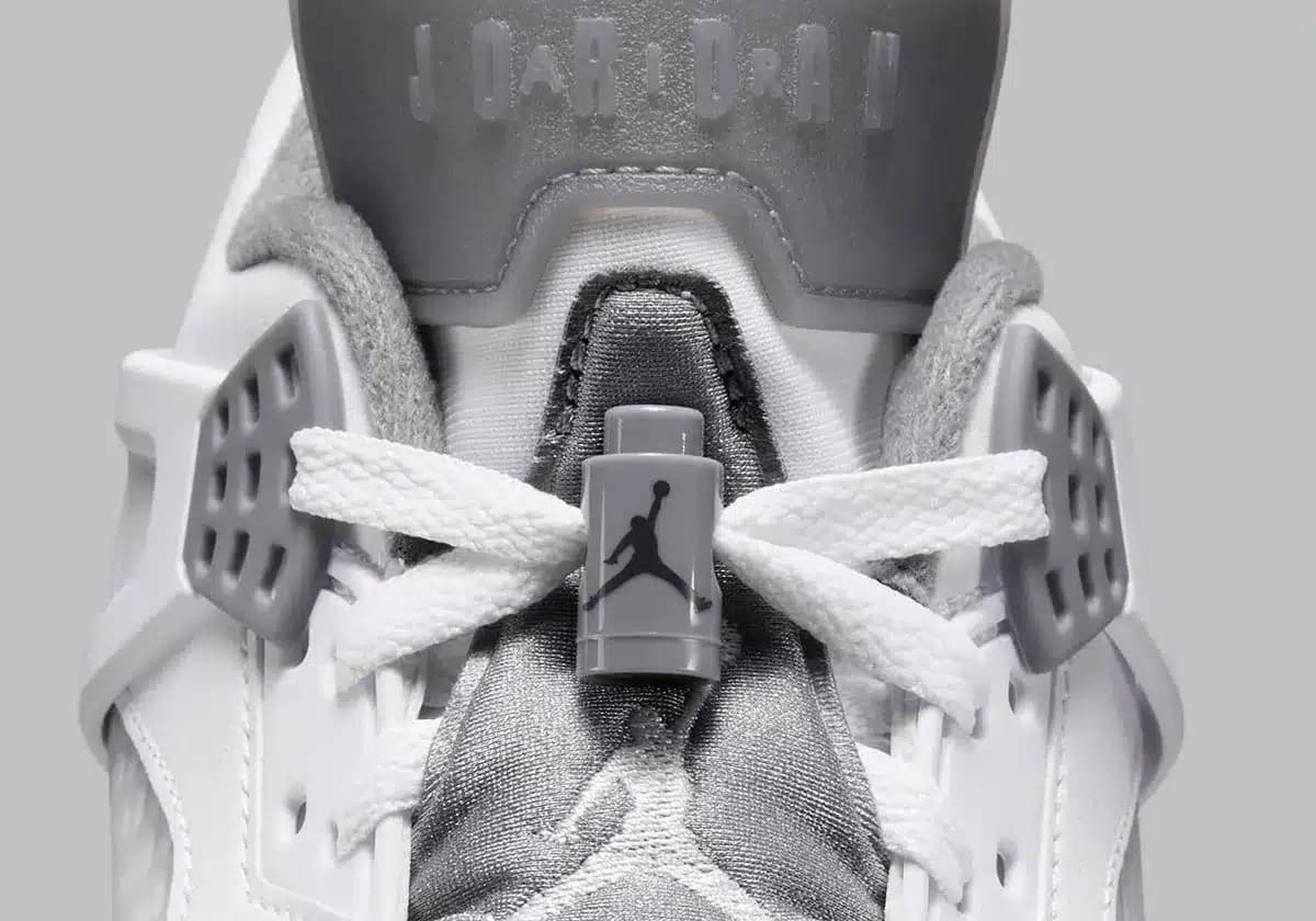 Close-up of a white and gray sneaker focusing on the laces, featuring the Jumpman logo and the word 'Jordan' embossed on the tongue.