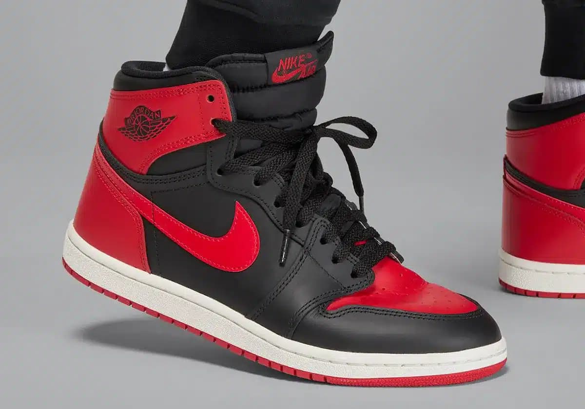 Close-up of a black and red high-top sneaker with a white sole, featuring a prominent Nike swoosh logo and black laces.