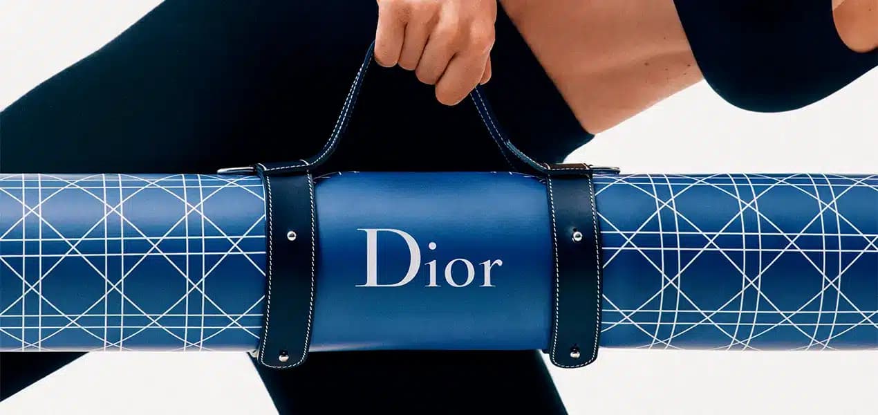 Person carrying a blue Dior yoga mat with geometric white lines