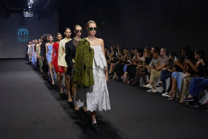 Models walk a runway in a fashion show as an audience watches from both sides