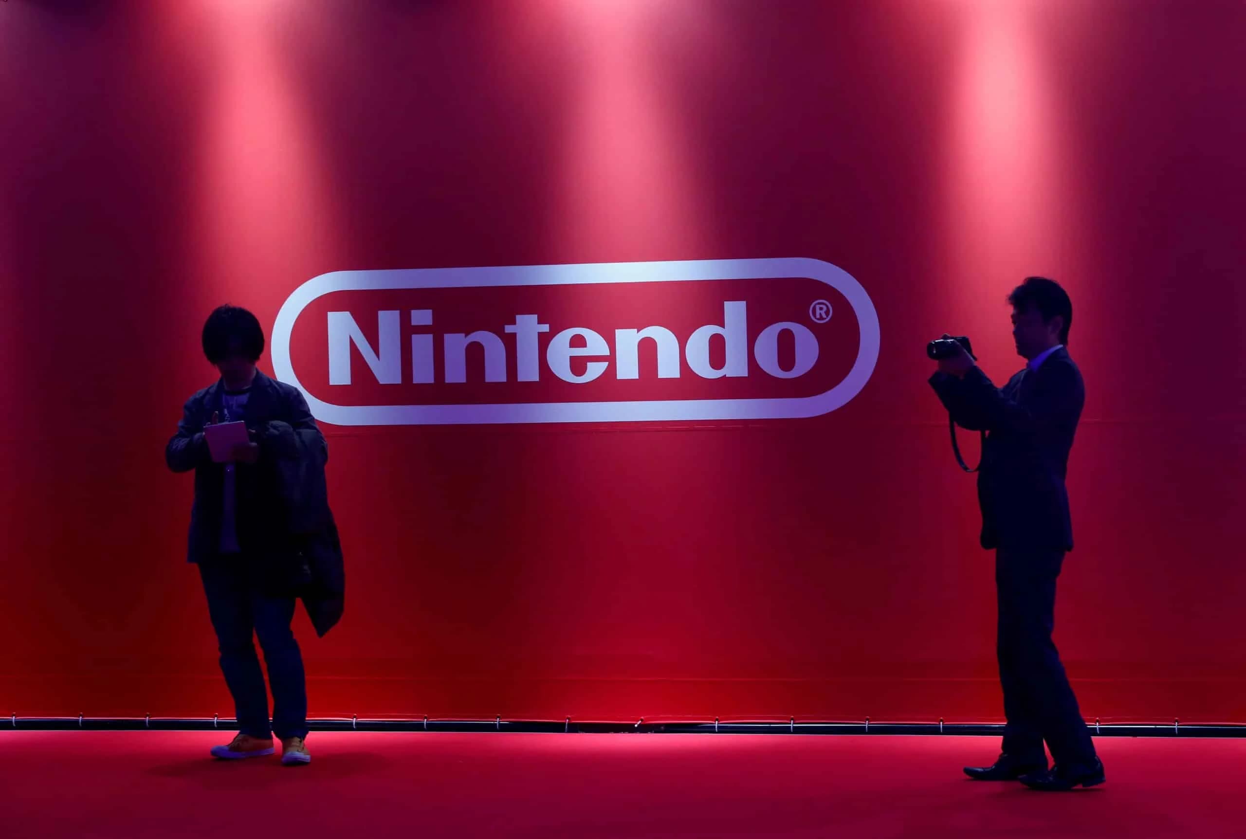 Two people silhouetted in front of a red backdrop with the Nintendo logo.