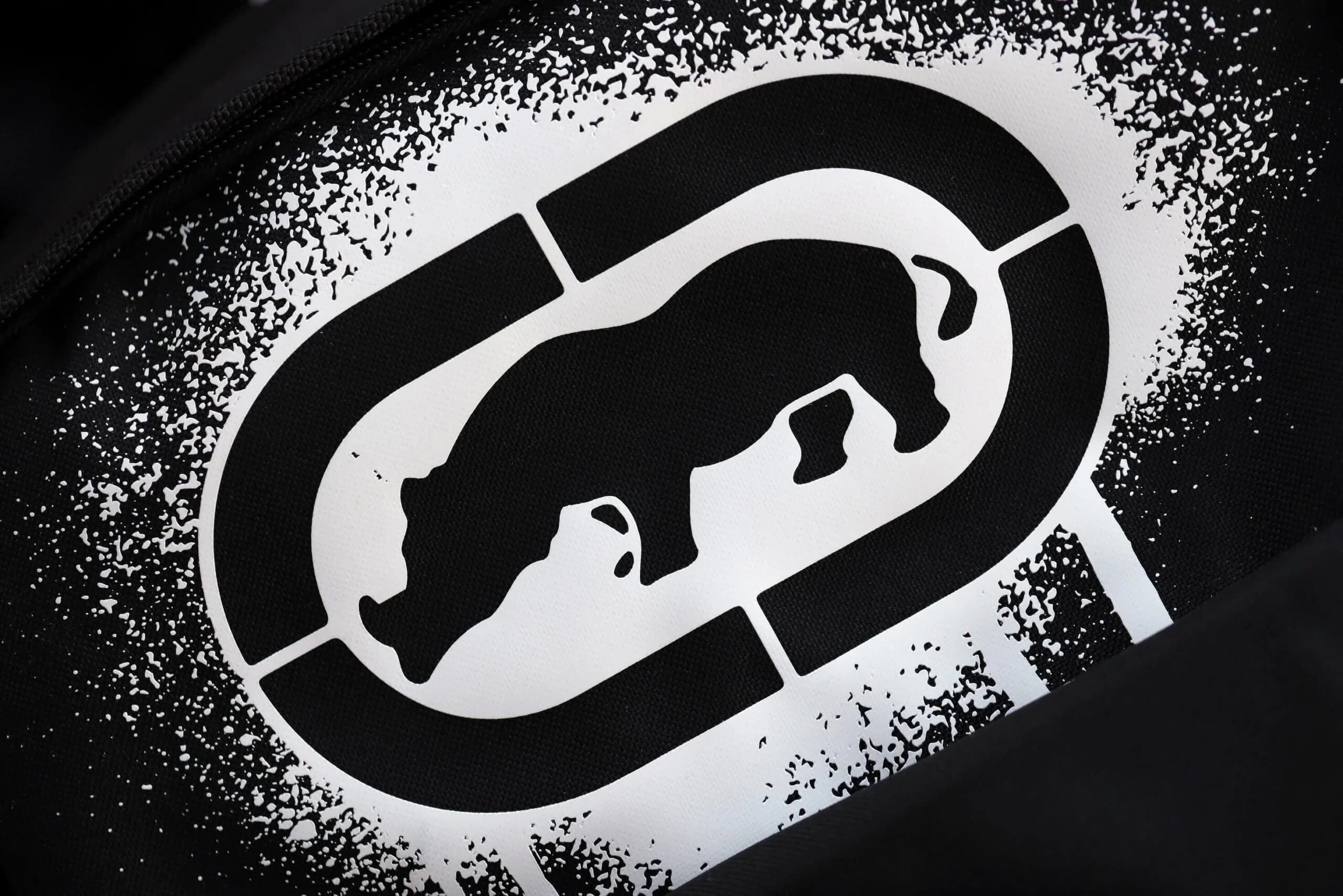 A black and white image showing the silhouette of a rhinoceros inside an oval shape, with a speckled texture surrounding it.
