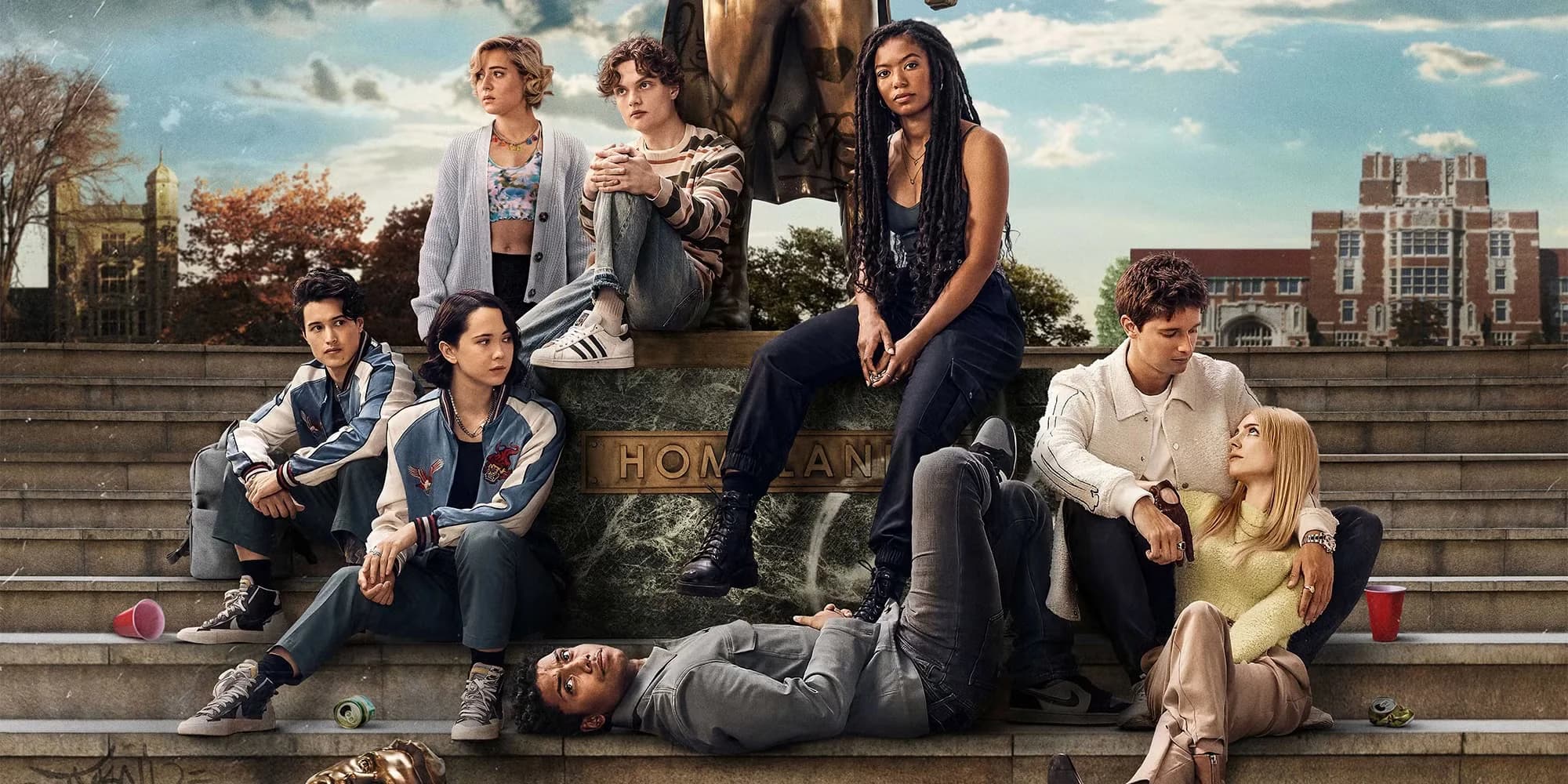 A group of young adults sitting on stone steps in front of a statue and a university building, with a mix of casual and relaxed postures.