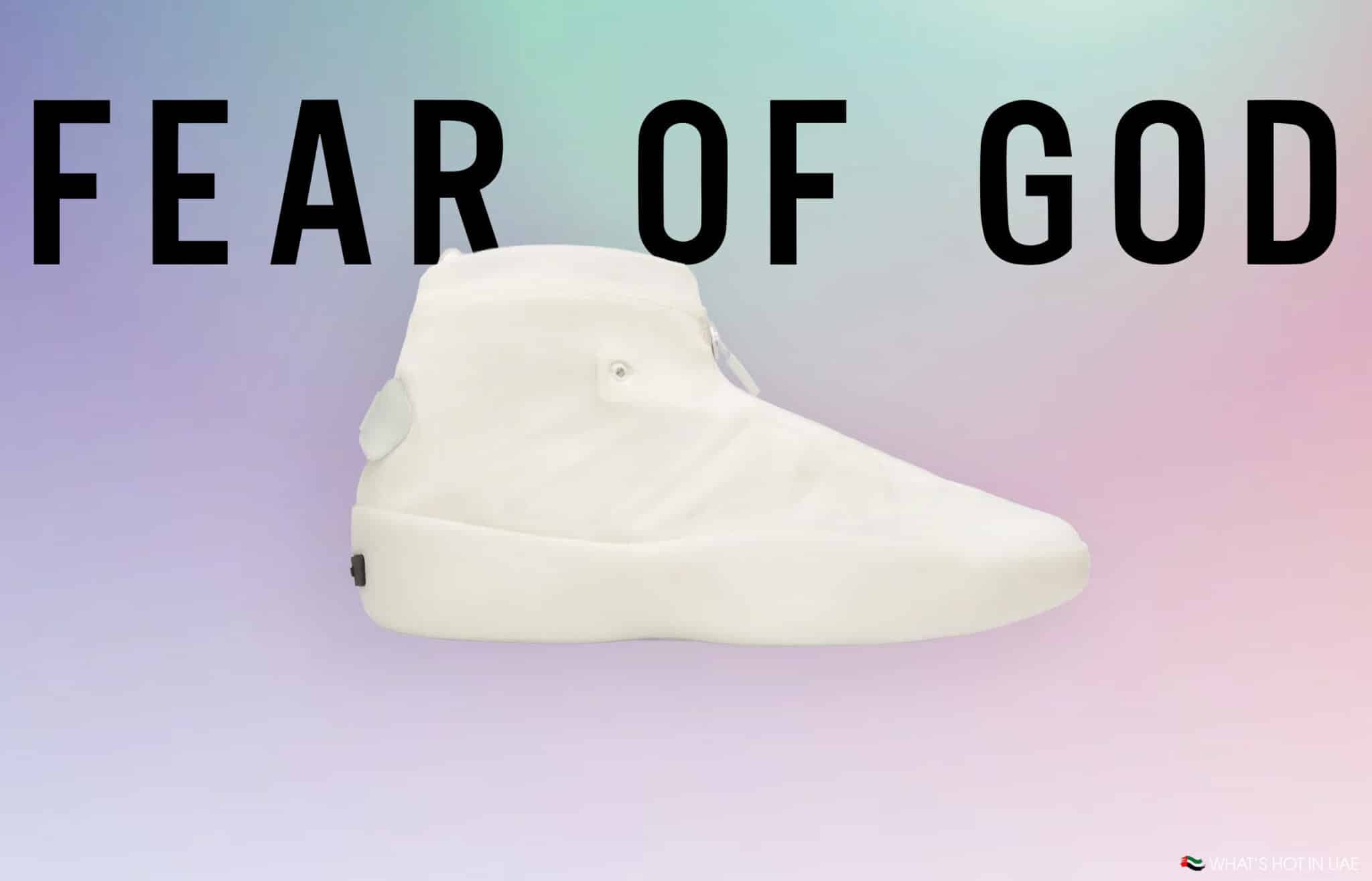 A high-top white shoe from Fear of God displayed on a soft gradient background with the brand name written in large black letters.