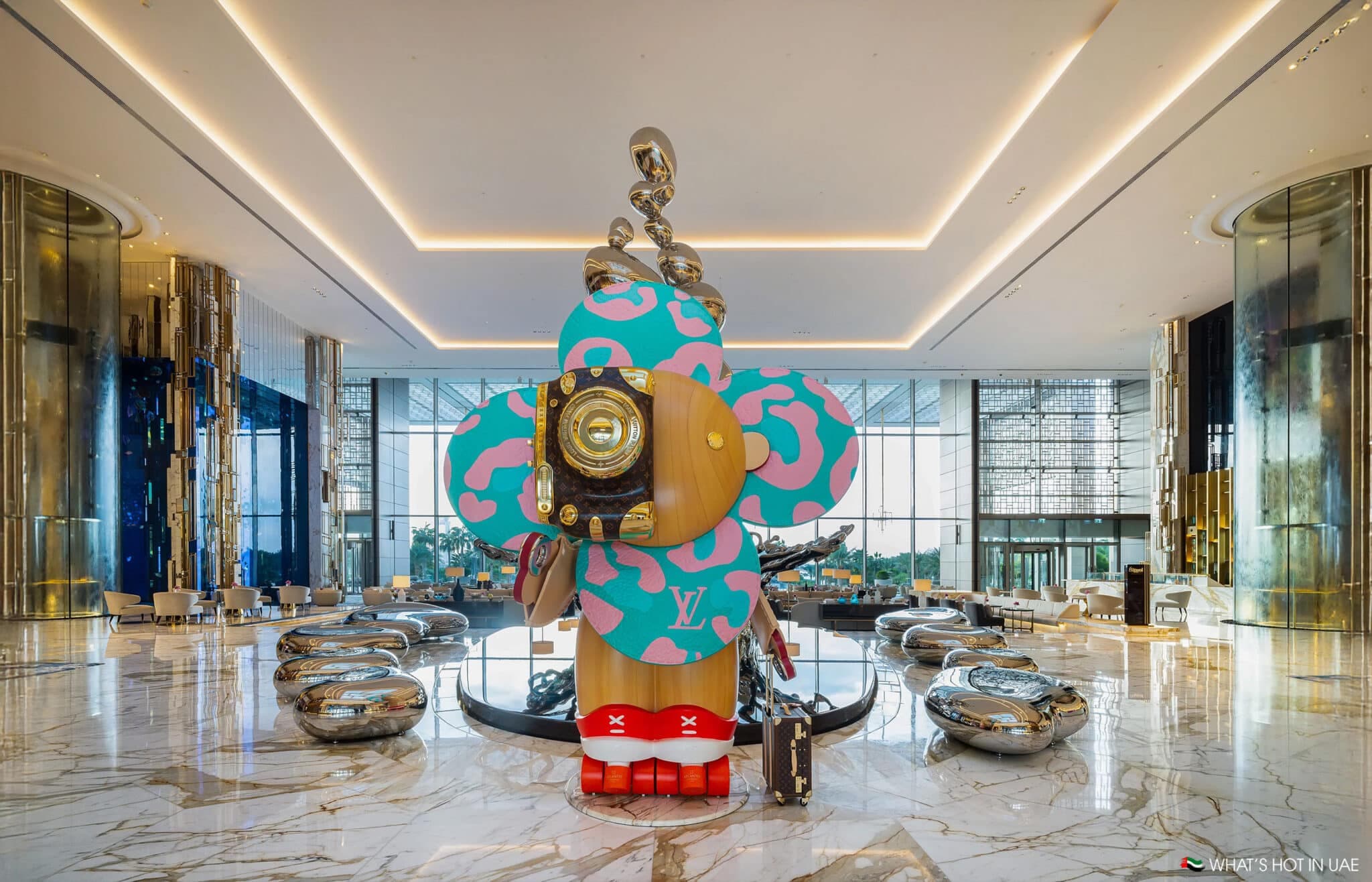 Large, colorful flower-like sculpture with abstract designs displayed in a modern, spacious lobby with sleek decor.