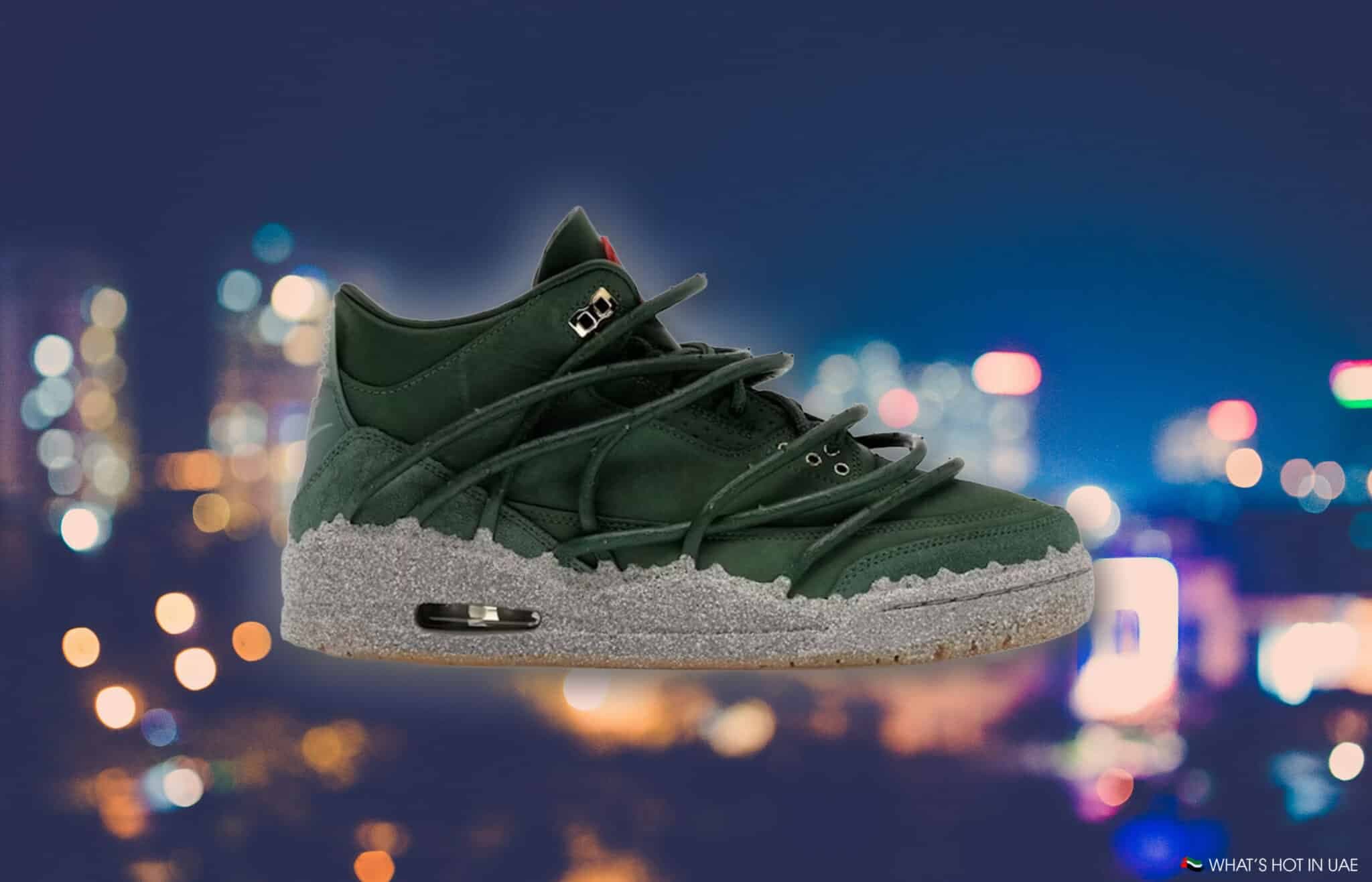 A green high-top sneaker with an intricate lacing design and a speckled gray sole, set against a blurred city lights backdrop.