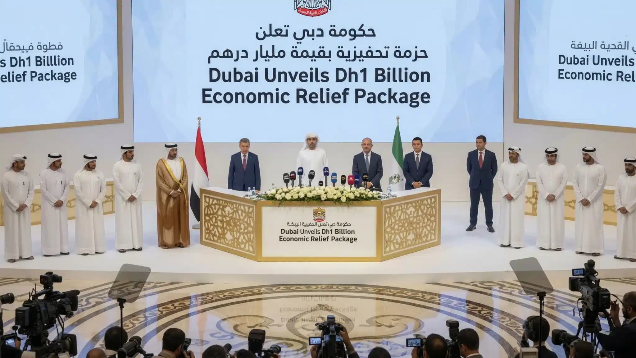 A group of officials stands at a podium during a press conference announcing Dubai's Dh1 billion economic relief package, with numerous cameras in the foreground.