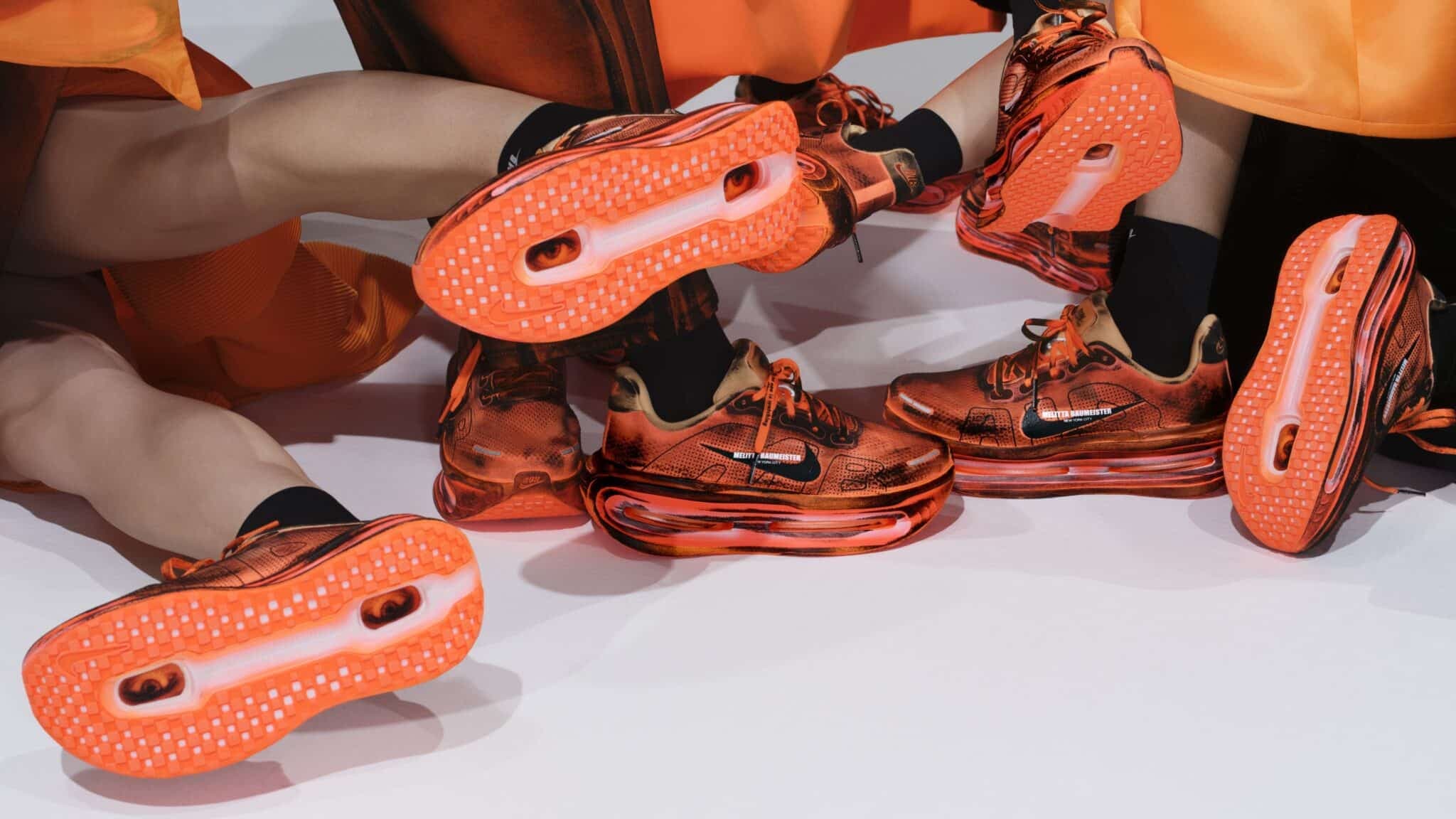 Several people wearing bright orange sneakers with translucent soles and Nike logos, arranged on a white surface.
