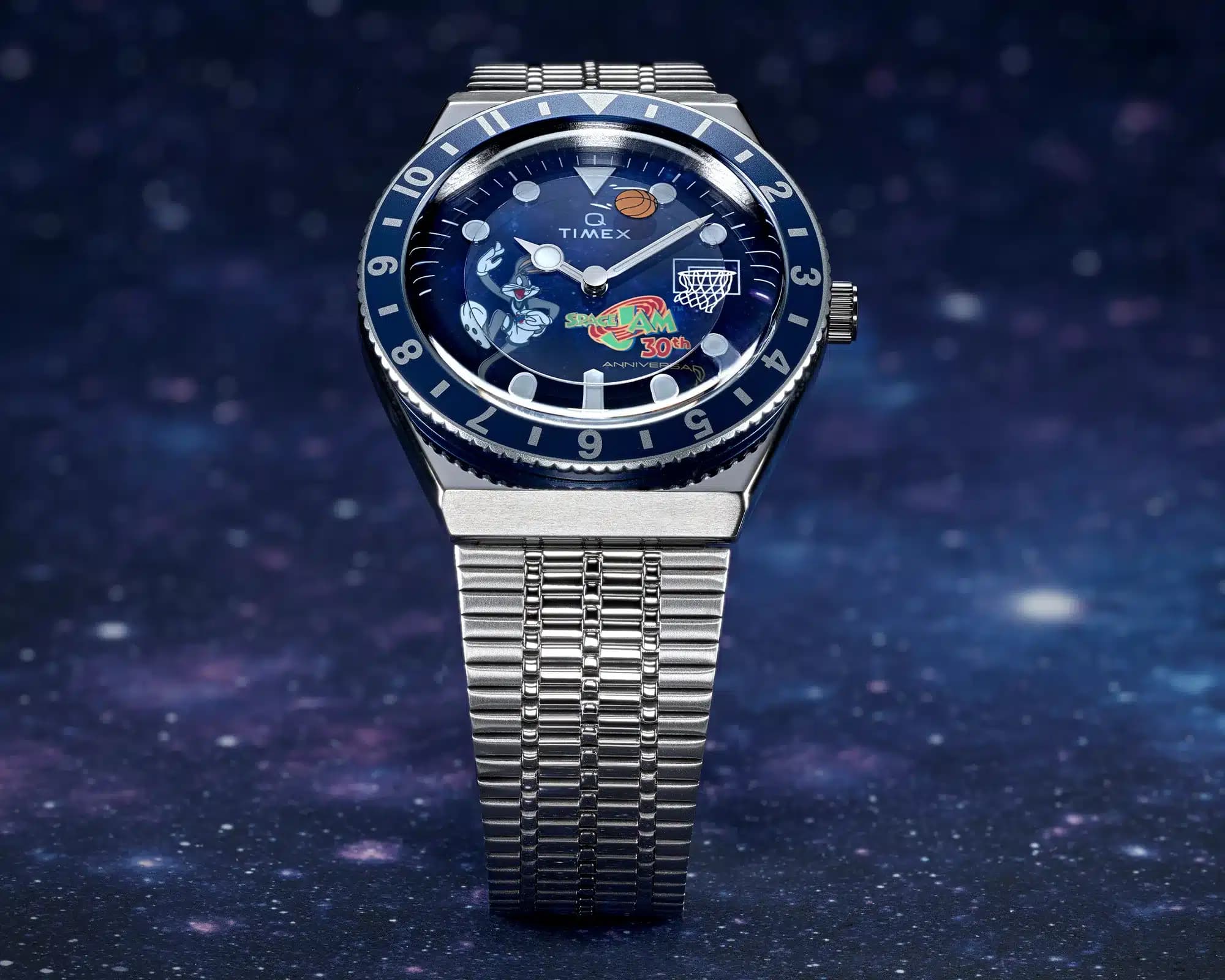 A wristwatch with a silver metal band and a blue dial featuring colorful Space Jam themed graphics and a basketball hoop.