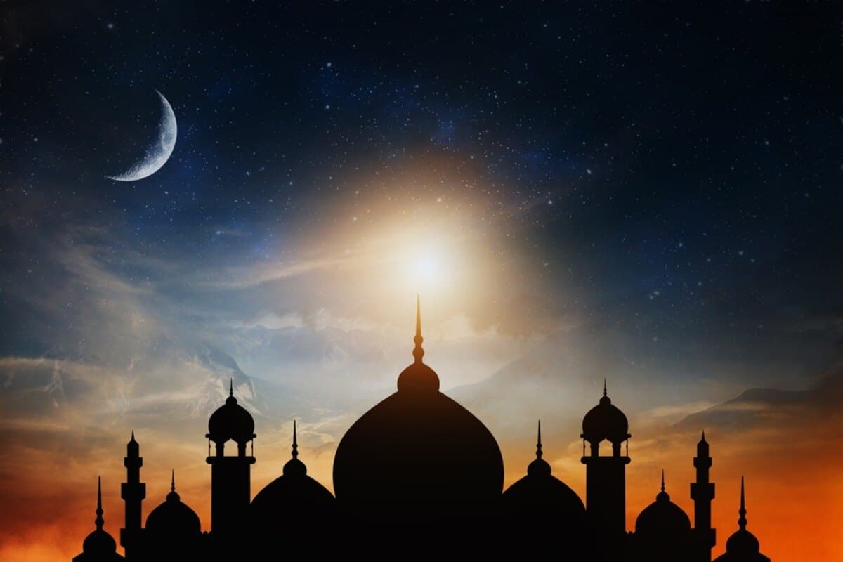 Silhouette of a mosque under a starry sky with a crescent moon and a glowing sunset.