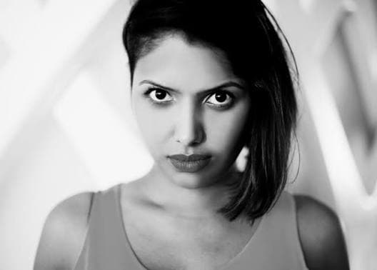 Black-and-white portrait of a woman with a serious expression and side-swept hair on one shoulder