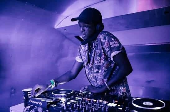 DJ performing at a mixer under purple lighting in a club-like setting