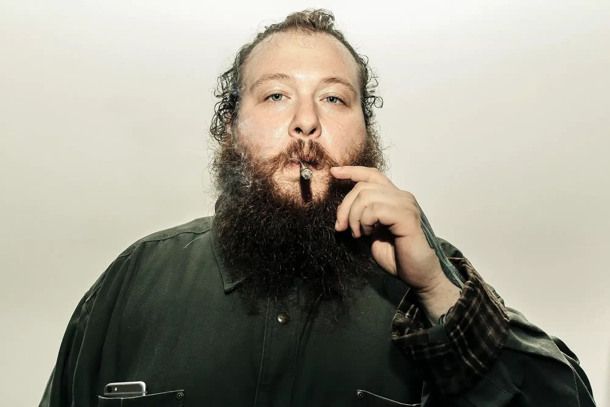 Bearded man holding a cigar between his lips and wearing a dark shirt