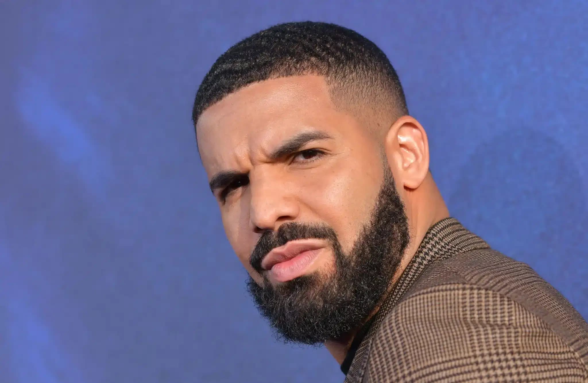 Close-up portrait of a bearded man making a skeptical expression against a blue background