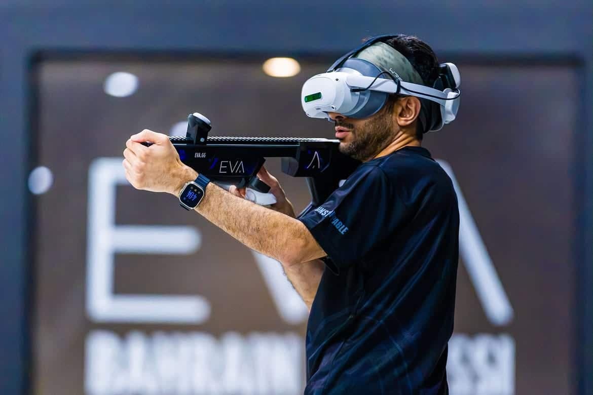 Man wearing a virtual reality headset aims a futuristic rifle controller during a gaming event