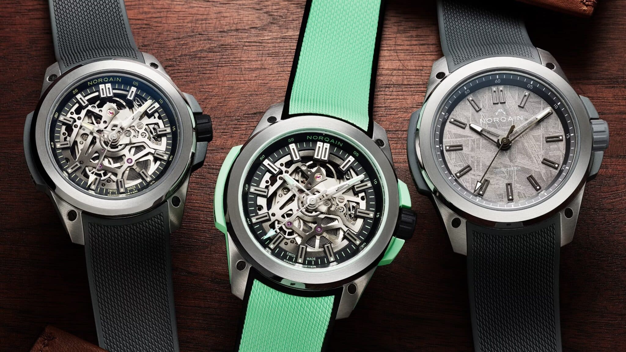Three NORQAIN wristwatches with textured rubber straps, including two skeletonized dials and one silver patterned dial