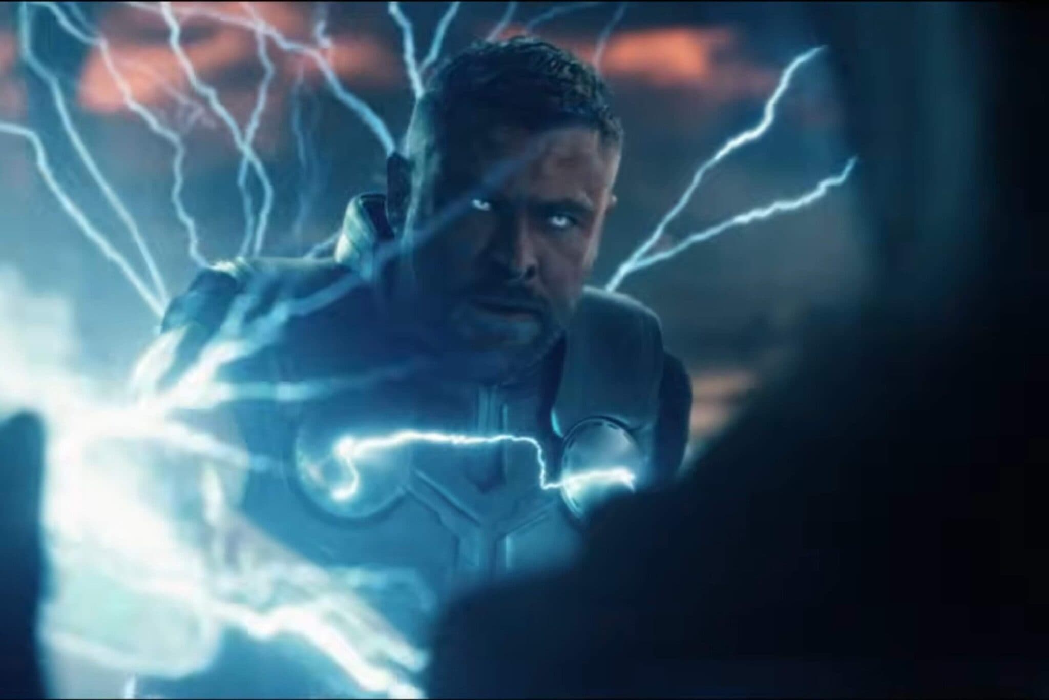 A man with glowing eyes reaches forward as blue lightning arcs around him