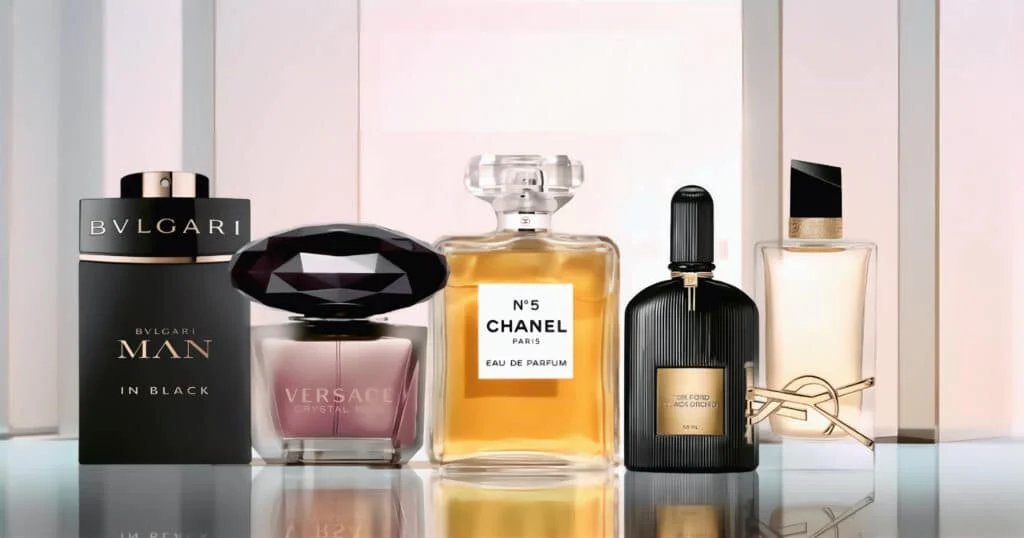 A collection of five luxury perfume bottles displayed in a row, featuring brands Bvlgari, Versace, Chanel, Tom Ford, and Yves Saint Laurent, each with distinct bottle designs and labels.