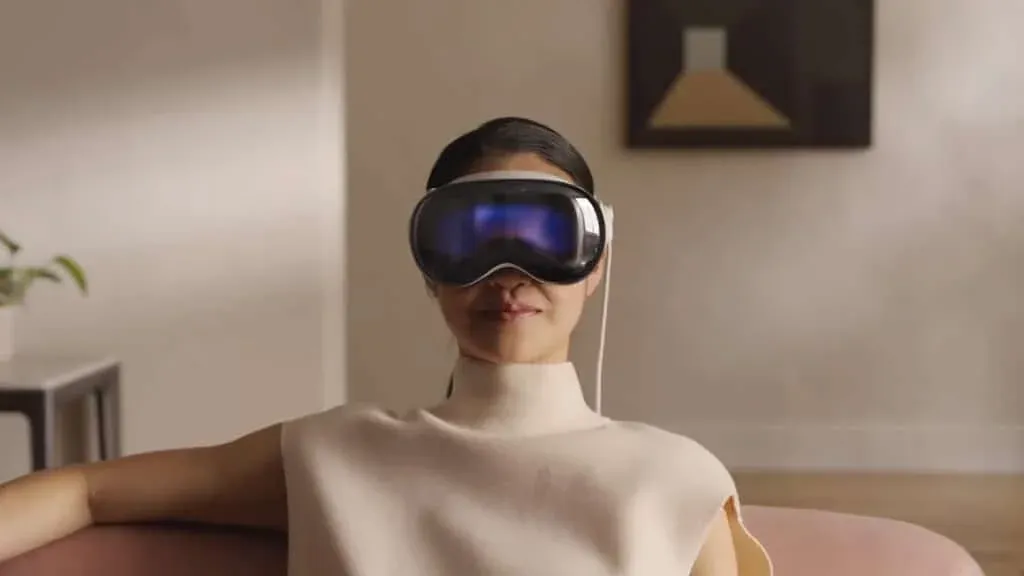 A person sitting on a couch wearing a virtual reality headset in a modern, minimalistic living room with a plant and abstract wall art in the background.