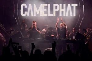 A DJ duo performs on stage with a large "CAMELPHAT" sign in the background, surrounded by a lively crowd.