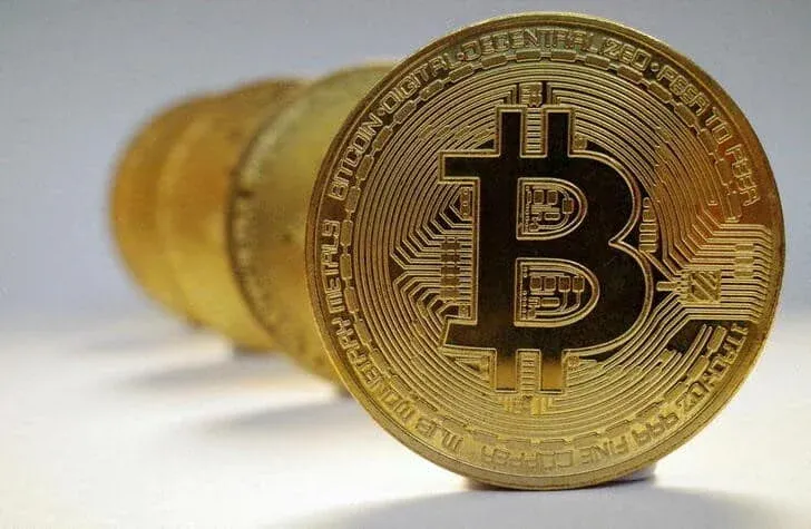 A stack of golden coins with the Bitcoin symbol prominently displayed on the front coin.
