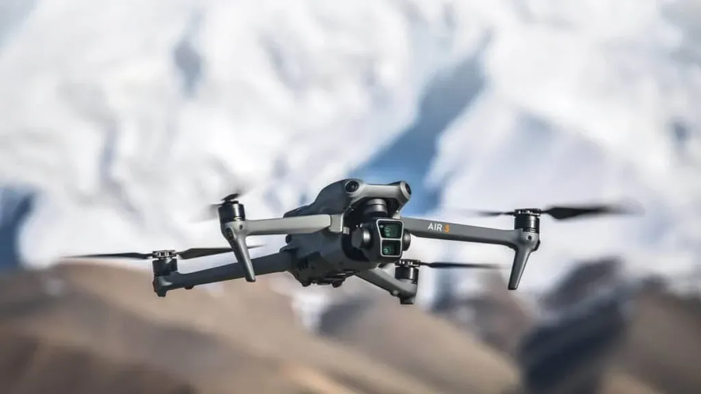 A gray quadcopter drone labeled 'AIR 3' flying with a mountainous, snow-covered background.