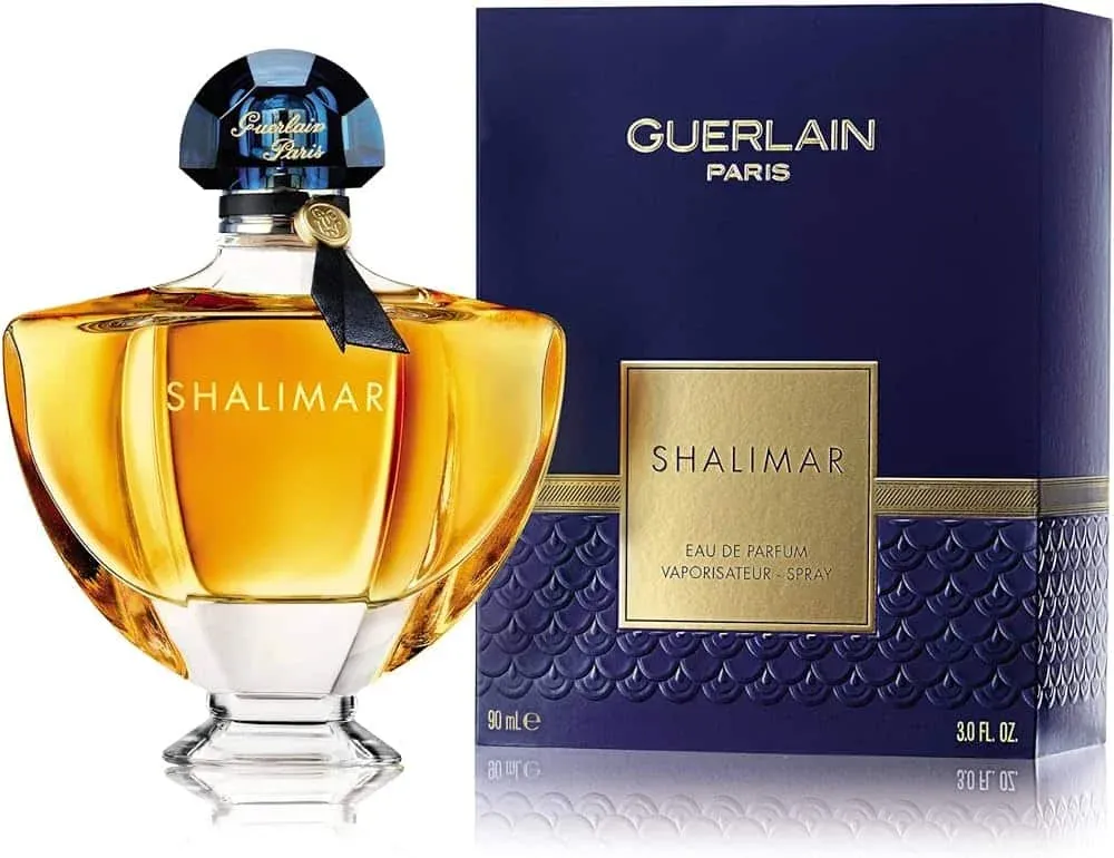 A bottle of Shalimar Eau de Parfum by Guerlain Paris next to its elegant blue box packaging.