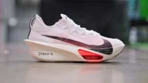White running shoe with an oversized sole, featuring a distinctive red and black color pattern and numbering '20820-4' on the side, displayed against a blurred background.