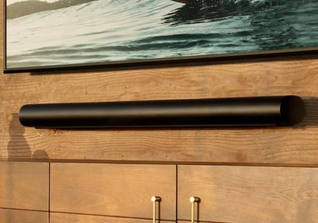 A sleek black soundbar mounted on a wooden wall beneath a framed piece of artwork.