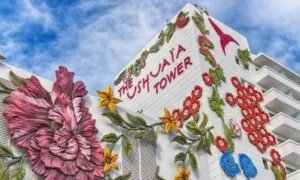 Building known as The Ushuaïa Tower adorned with large, colorful flower sculptures on its exterior walls against a blue sky backdrop.