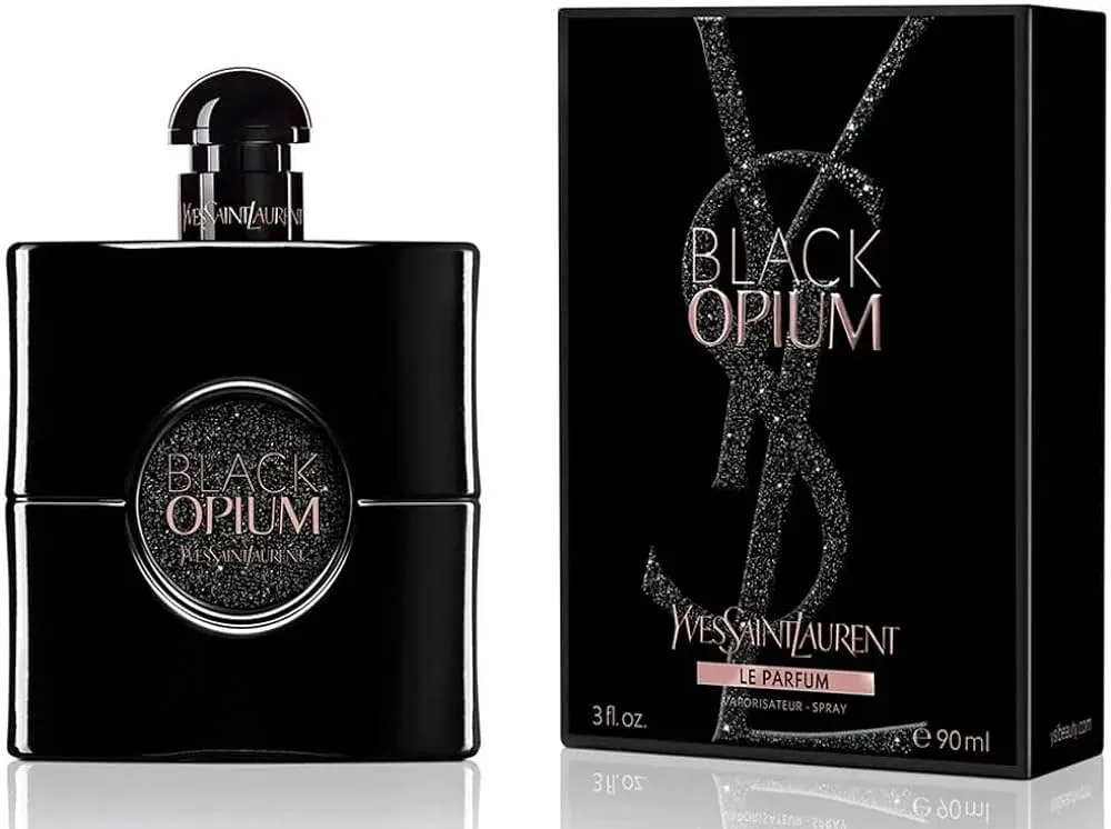 A bottle and box of Yves Saint Laurent Black Opium Le Parfum fragrance, featuring a sleek black design with glittery accents and pink lettering, with the bottle having a circular window showing the name.