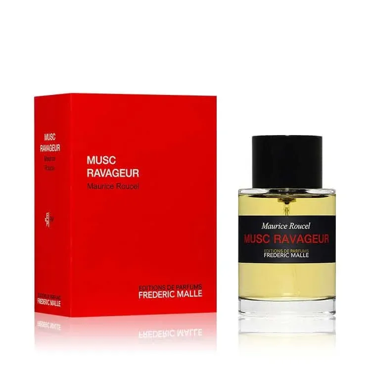 A bottle of Musc Ravageur by Maurice Roucel, with a red box next to it. The bottle is clear with a black label and a black cap, and it contains a yellow liquid.