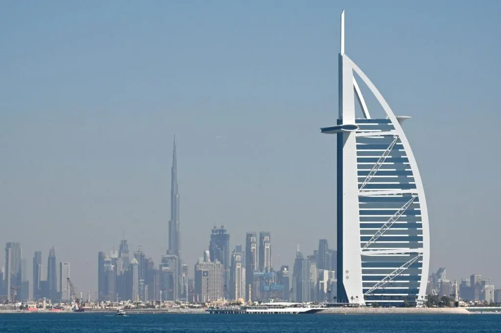 A view of Dubai's skyline featuring the Burj Al Arab in the foreground, with its distinctive sail-shaped design, and the Burj Khalifa visible in the background, the tallest structure on the horizon.