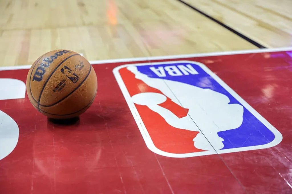 A basketball on a court with the NBA logo prominently displayed on the floor.