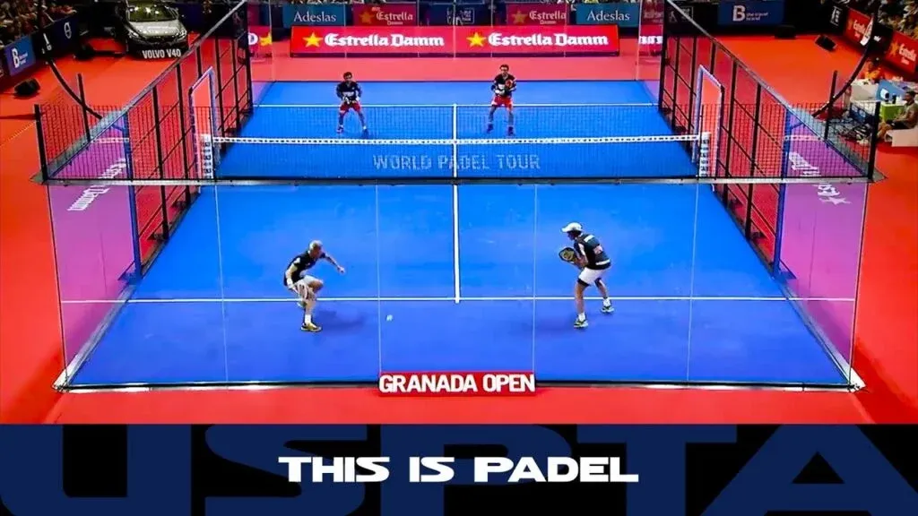 Two teams playing padel on an enclosed court during the World Padel Tour's Granada Open, with spectators in the background and banners displaying 'Estrella Damm'.