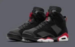 Pair of black and red sneakers featuring perforated design and visible air sole units, showcased against a dark gray background.