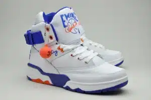 Pair of white high-top sneakers with blue and orange accents, featuring the word 'Ewing' and a basketball logo on the tongue, and an orange basketball keychain with the number 33 attached.