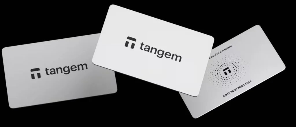 Three Tangem cards displayed at different angles on a black background, featuring the Tangem logo and a serial number.