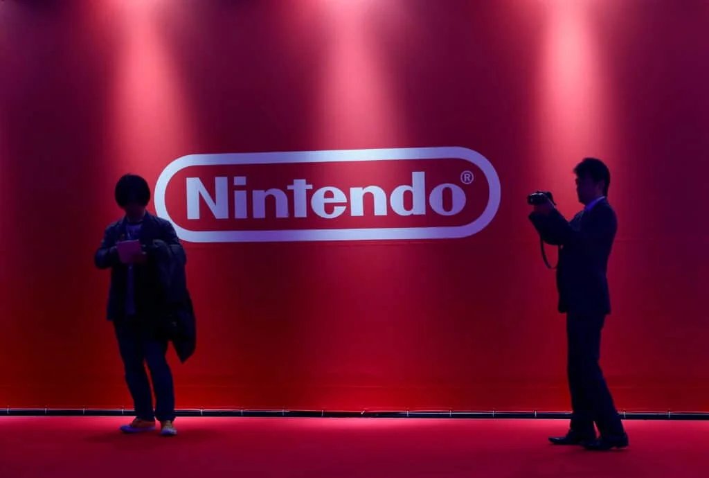 Two people silhouetted in front of a red backdrop with the Nintendo logo.