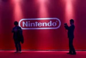 Two people silhouetted in front of a red backdrop with the Nintendo logo.