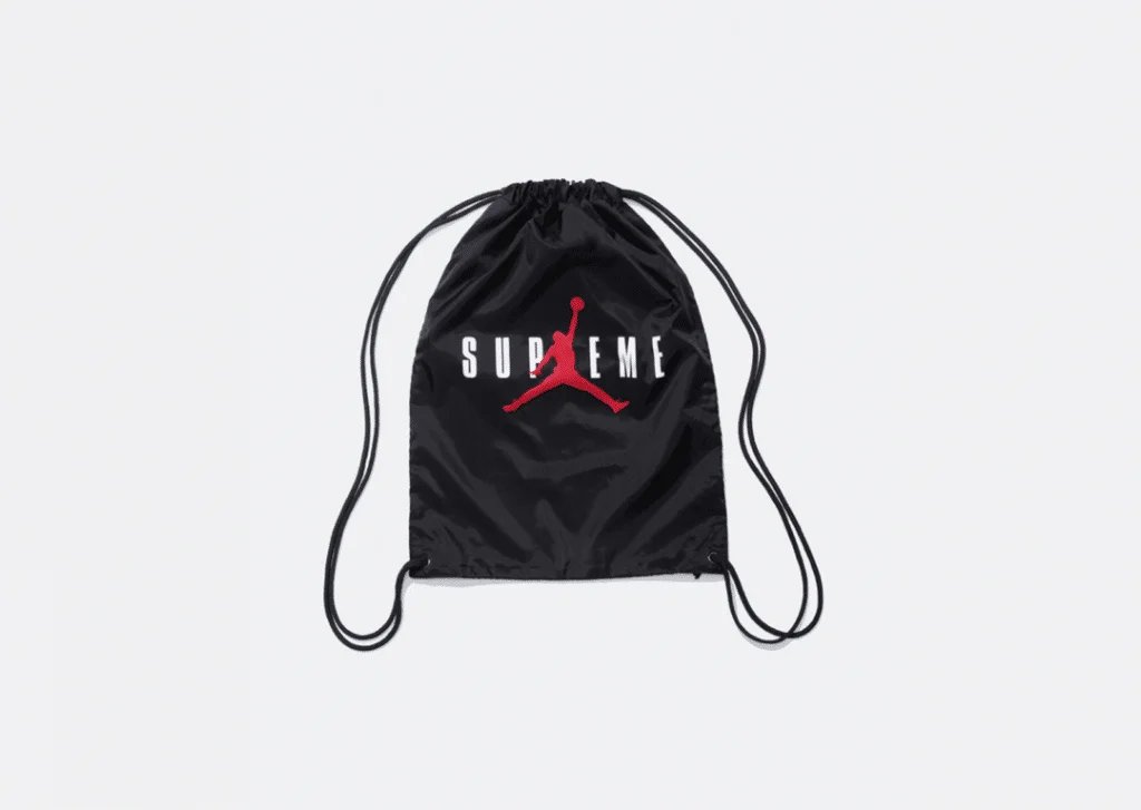 Black drawstring backpack with a red silhouette of a basketball player dunking and the word 'SUPREME' printed in white across the front.