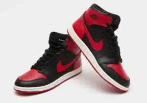 A pair of high-top sneakers in black and red leather with red Nike swooshes, featuring perforated toe boxes and white midsoles with red outsoles, displayed against a white background.