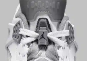 Close-up of a white and gray sneaker focusing on the laces, featuring the Jumpman logo and the word 'Jordan' embossed on the tongue.