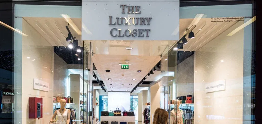 The entrance of 'The Luxury Closet' retail store with mannequins and luxury handbags on display inside.
