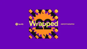 A promotional graphic for Spotify Wrapped 22 on a purple background, featuring the word 'Wrapped' over a vibrant orange and yellow design with the number '22' and yellow geometric shapes. The Spotify logo and hashtag #SPOTIFYWRAPPED are also displayed.