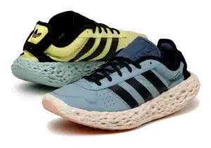 A pair of Adidas sneakers with a distinctive design, featuring a perforated sole and a two-tone color scheme with blue and yellow uppers, complemented by the classic black Adidas stripes.