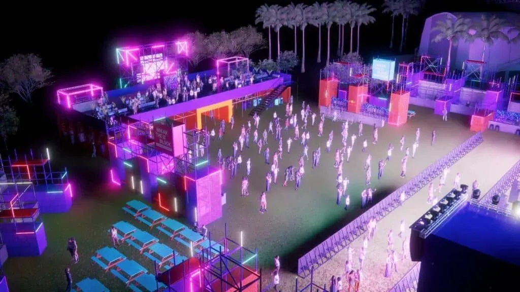 An outdoor event space at night, illuminated with vibrant neon lights in various colors. The area features structured platforms and a stage with people gathered around. Several palm trees are visible in the background.