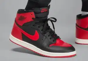 Close-up of a black and red high-top sneaker with a white sole, featuring a prominent Nike swoosh logo and black laces.