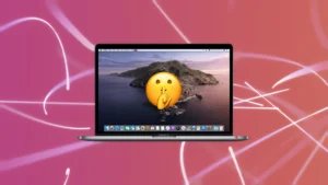 A MacBook Pro laptop displaying a mountain landscape wallpaper and a large shushing emoji on the screen, set against a pink background with abstract white lines.